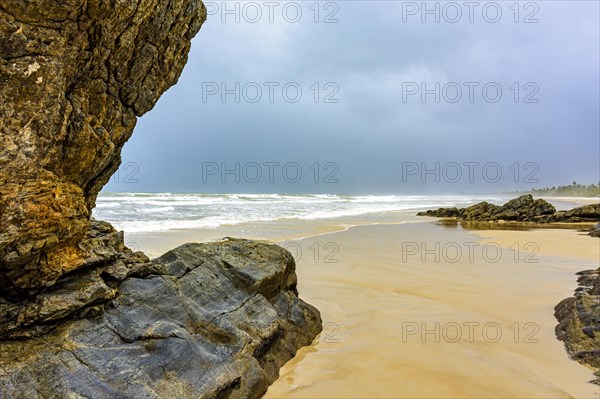 Deserted beach with coconut trees and rocks on a rainy day in Serra Grande on the coast of Bahia