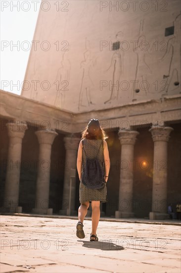 A young tourist wearing a cap visiting the Edfu Temple at sunrise in Aswan. Egypt