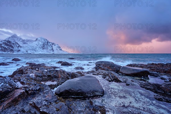 Beach of Norwegian sea on rocky coast in fjord on sunset in winter. Vareid beach
