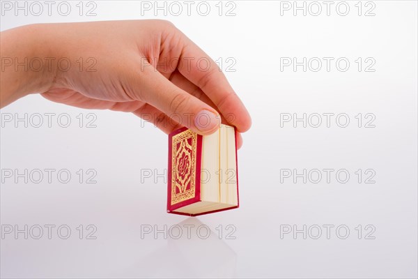 Hand holding The Holy Quran on a white background