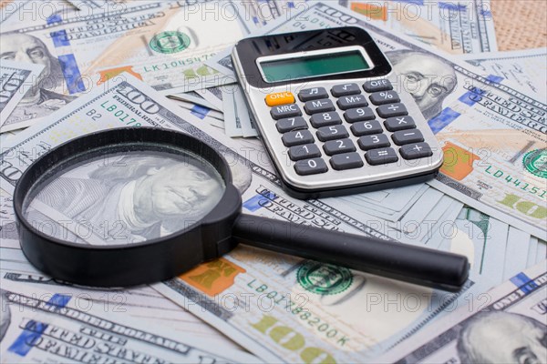 Magnifying glass is held over the banknote bundle of US dollar