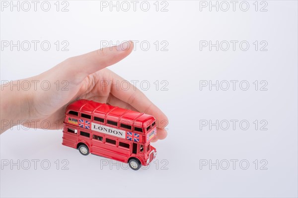 Child hand playing with London double decker bus model on white background