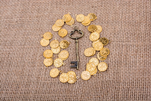 Hand holding a retro styled key over fake gold coins