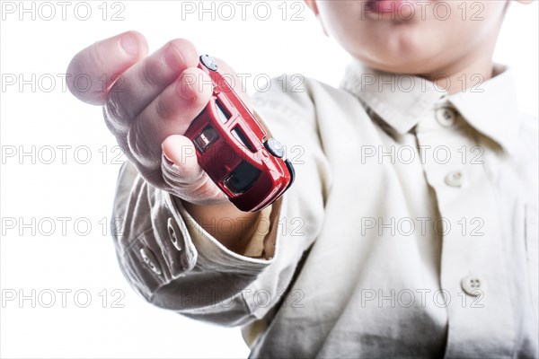 Baby hand holding a red car on a white background