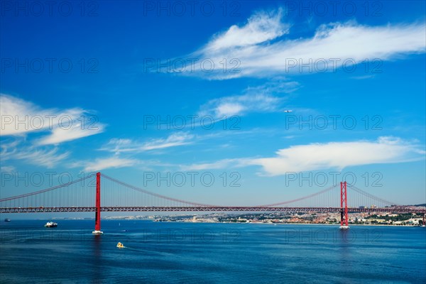 View of 25 de Abril Bridge famous tourist landmark of Lisbon connecting Lisboa to Almada on Setubal Peninsula over Tagus river with boats yachts