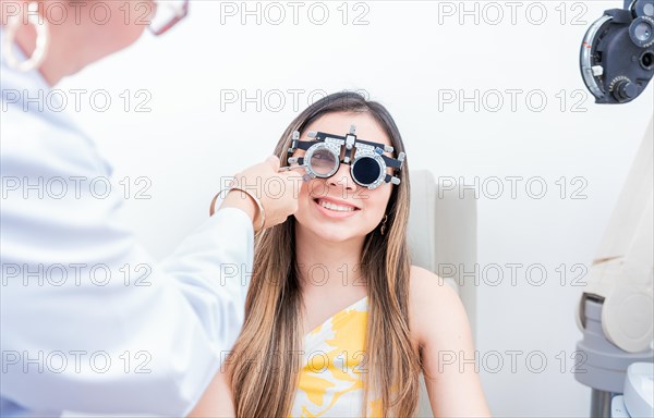 Smiling patient with optometrist trial frame. Closeup of optometrist examining patient with optometrist trial frame