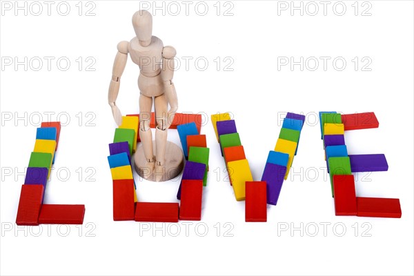 Wooden puppet standing amoung colorful dominos which write love