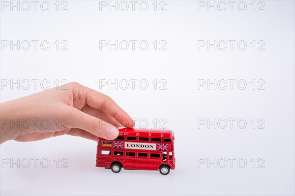 Child hand playing with London double decker bus model on white background