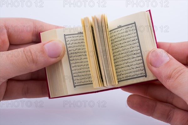 Hand holding The Holy Quran on a white background