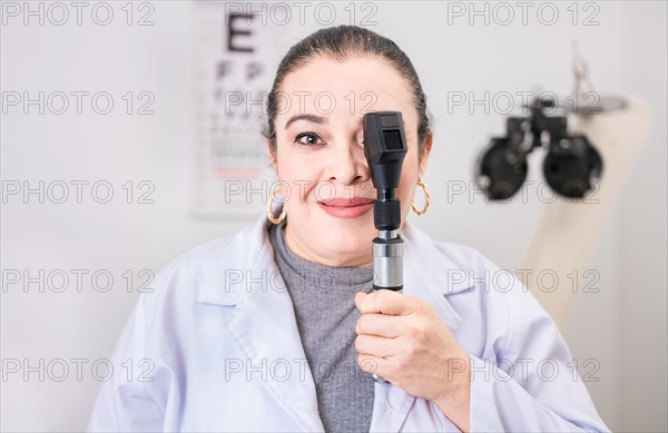 Portrait of female optometrist with ophthalmoscope in the laboratory. Smiling oculist holding an ophthalmoscope in the laboratory