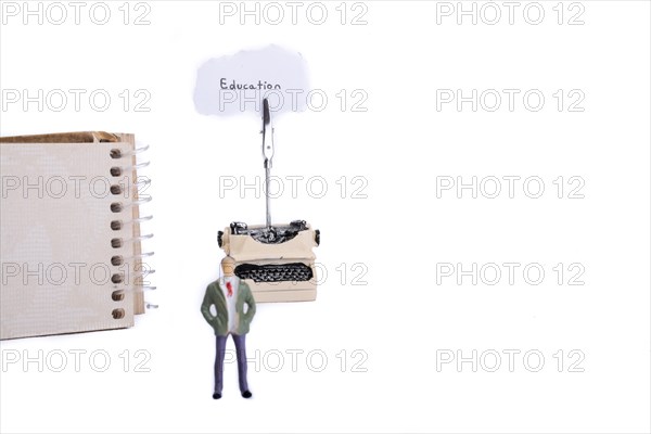 Man standing in front of a typewriter and a spiral notebook on a white background