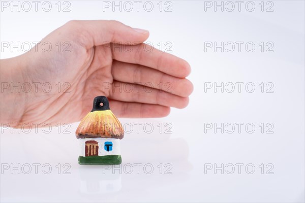 Hand holding a small traditional hut on a white background