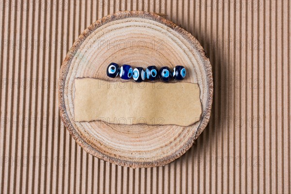 Evil eye beads and piece of burnt paper on wood log