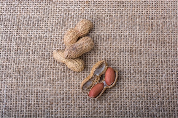 Cracked open peanuts with shell on a linen canvas background