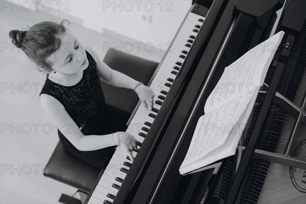 Elegant girl sits at the concert grand and plays the piano