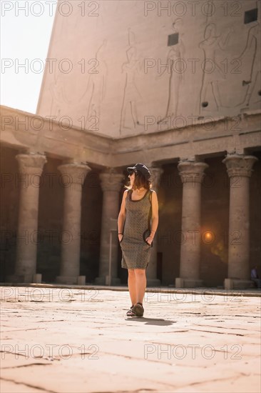 A young tourist wearing a cap visiting the Edfu Temple at sunrise in Aswan. Egypt