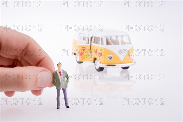 Hand holding a human figure near a peace van on a white background