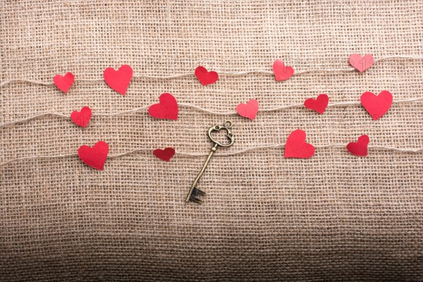 Love concept with heart shaped papers and key on linen threads