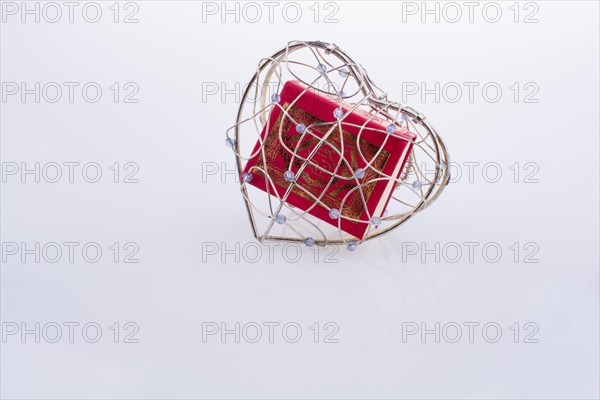 The Holy Quran in a heart shaped cage on a white background