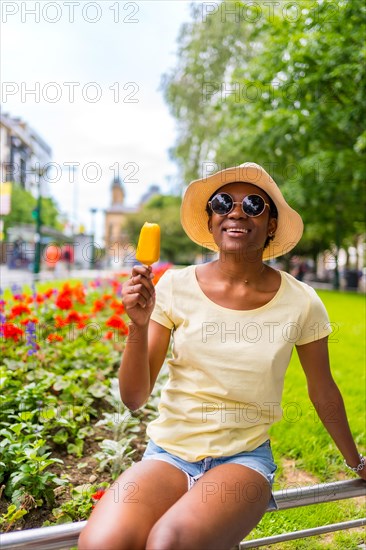 African black ethnicity woman eating a mango ice cream in the city