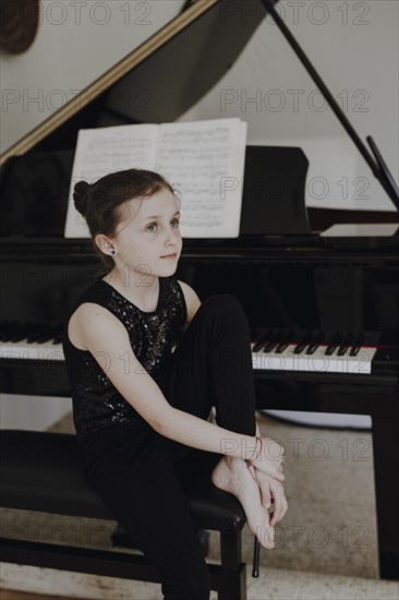 Elegant girl sits at the concert grand and plays the piano