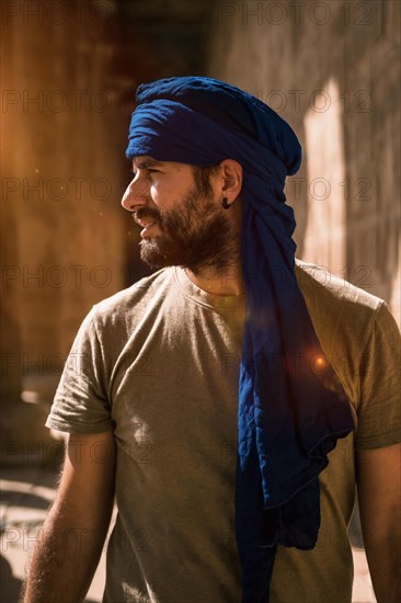 A young tourist in a blue turban visiting the Edfu Temple in the morning near Aswan city. Egypt