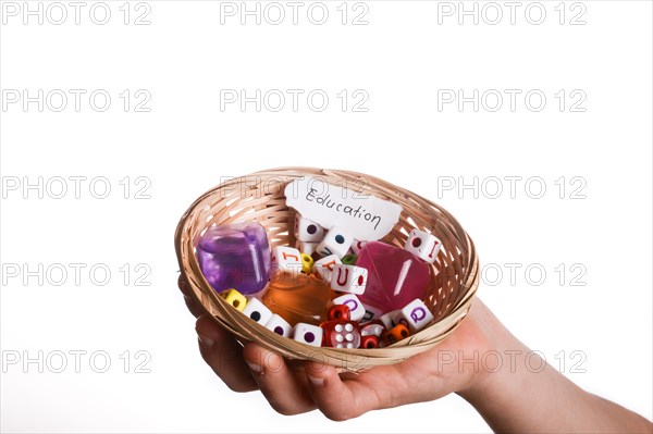 Child hand holding a education written a piece of torn paper in a basket full of letter cubes