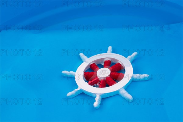 Little red and white color model boat steering wheel in water