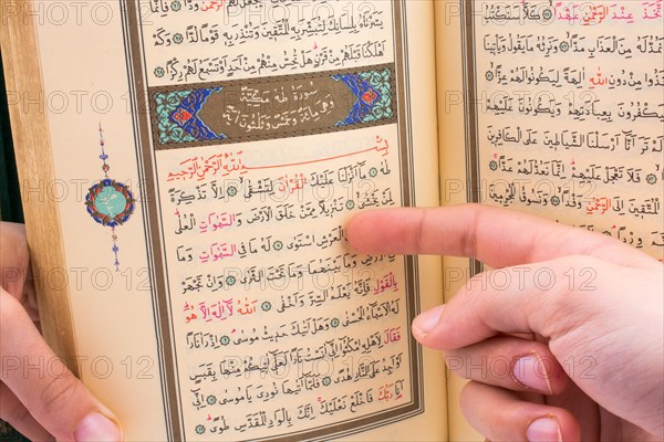 Hand holding The Holy Quran on a white background