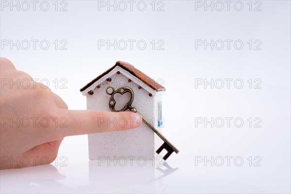 Hand holding a golden key near a house on a white background