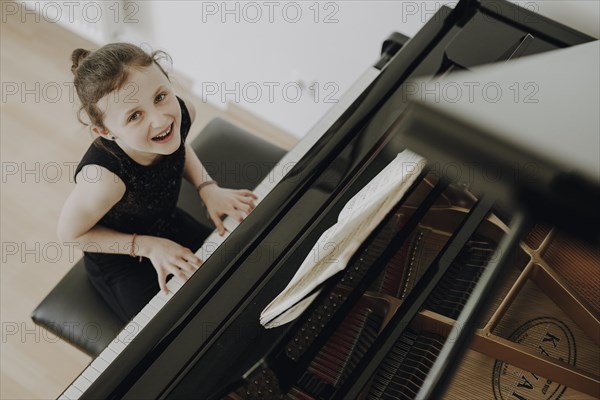 Elegant girl sits at the concert grand and plays the piano