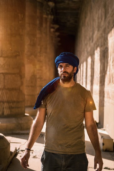 Young man in blue turban walking on the columns of the Edfu Temple near the city of Aswan. Egypt