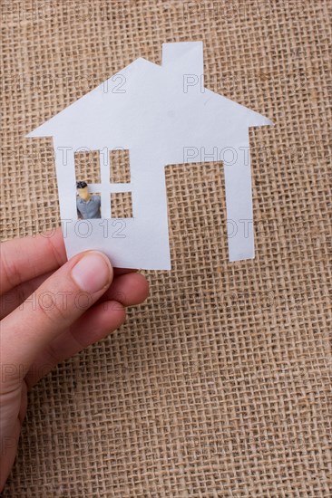 Paper house and a man figurine on a linen canvas background