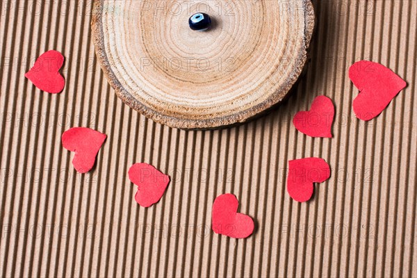 Bead on Piece of log with red paper hearts on cardboard