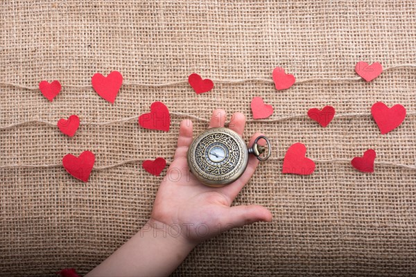 Love concept with pocket watch and paper hearts on threads