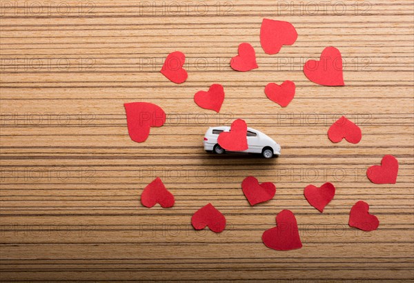Love concept with model car and heart shaped papers