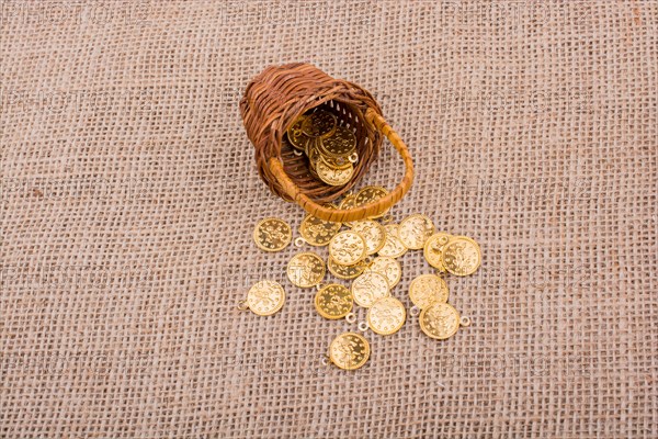 Fake gold coins out of a little basket on canvas