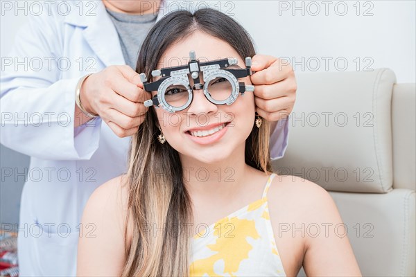 Young patient with optometrist trial frame. Hands of optometrist examining patient with optometrist trial frame