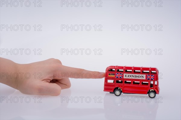 Child hand playing with London double decker bus model on white background