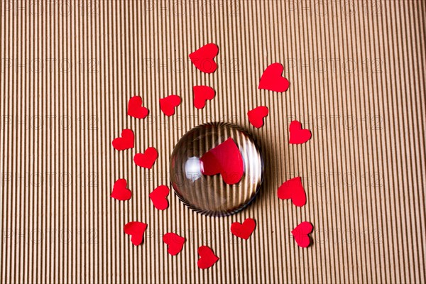 Red color paper hearts under and around half glass globe