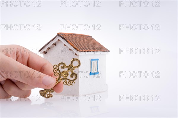 Hand holding a golden key near a house on a white background