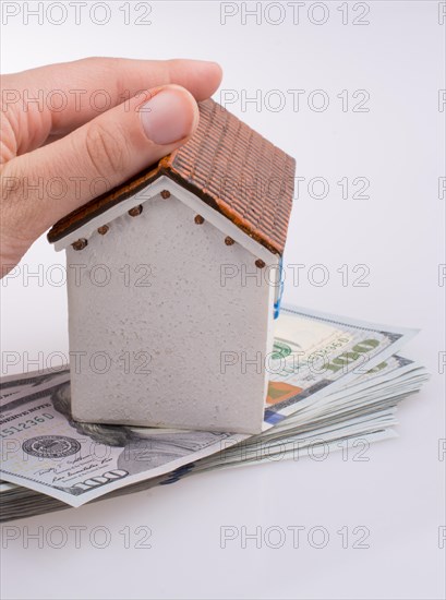 Hand holding a model house by the side of Turkish Lira banknotes on white background