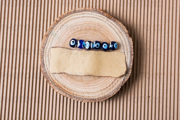 Evil eye beads and piece of burnt paper on wood log