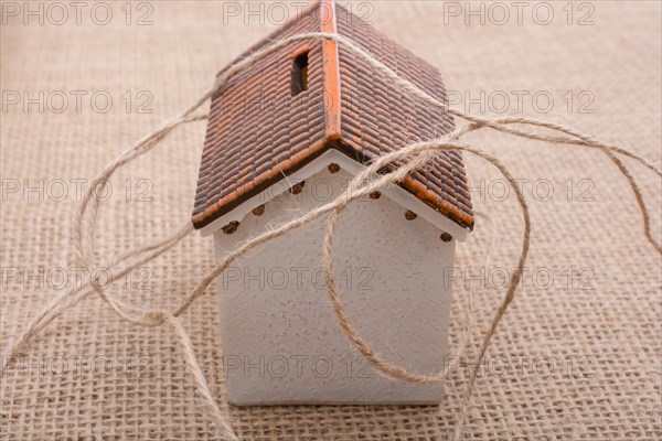 Thread wrapped around a model house on a brown background