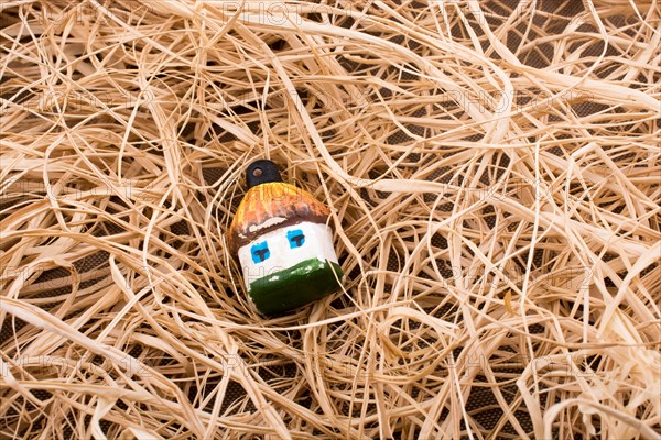 Little toy model hut placed on straw background