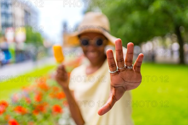 African black ethnicity woman eating a mango ice cream in the city in summer