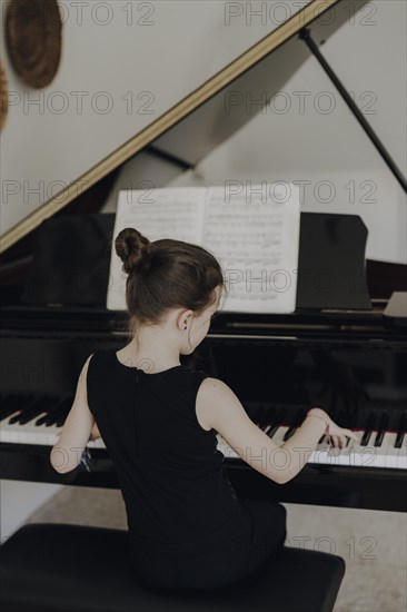 Elegant girl sits at the concert grand and plays the piano