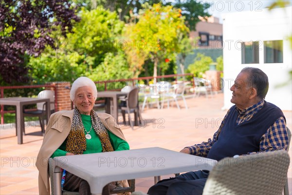 Two very cheerful elderly people in the garden of a nursing home