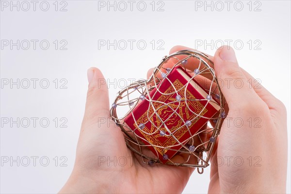 The Holy Quran in a heart shaped cage on a white background