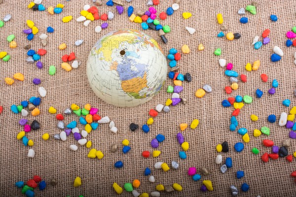 Model globe placed amid colorful pebbles